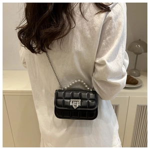 Detail of black quilted mini bag featuring elegant pearl handle and silver chain strap
