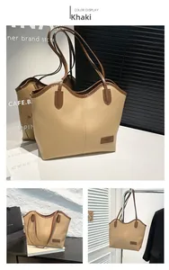 Detail view of khaki leather tote bag showing fashion tag and large shoulder strap design