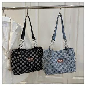 Detail of checkered tote bags with frayed edges, metal chains, and fashion leather tags