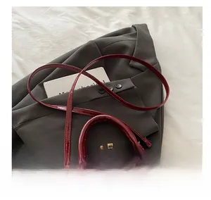Close-up of red patent leather shell bag with golden hardware on a grey blazer
