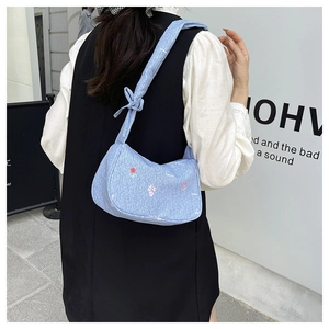 Close-up of light blue floral handbag with bow strap detail and red flower pattern