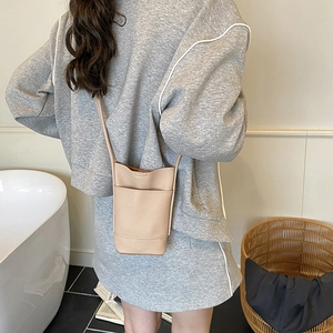 Minimalist beige pebble leather bucket crossbody bag for women on a model
