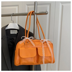 Detail of orange Boston bag featuring front pockets and lace bows on smooth PU leather