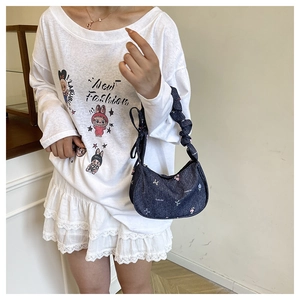 Detail of dark blue denim underarm bag featuring floral embroidery and a scrunchie handle