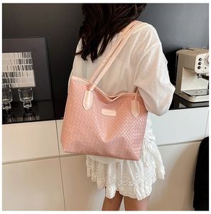 Close-up of pink woven tote bag showing leather texture and stylish metal brand plate