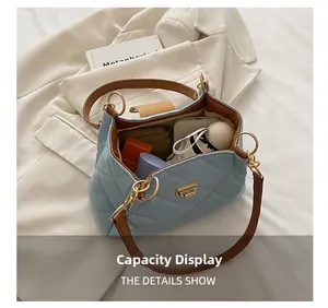 Spacious interior of light blue quilted tote bag showing phone, makeup, and umbrella