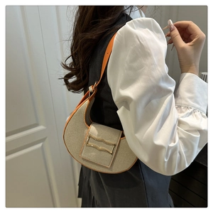 Close-up of crescent dumpling bag featuring beige woven fabric and vibrant orange leather trim