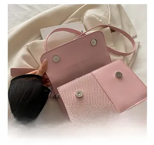 Close-up of silver magnetic closure on pink woven and leather flap crossbody bag
