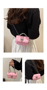 Detail view of mini pink quilted crossbody bag with pearl handle and metal chain strap