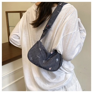 Detail of dark gray denim underarm bag with white bows and colorful floral embroidery