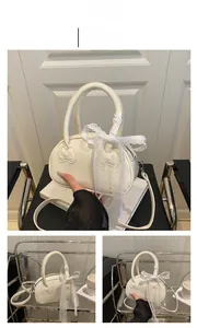 Detail of white leather handbag featuring a 3D bow relief and delicate lace ribbon