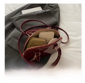 Macro shot showing internal capacity of red patent leather shell bag with daily items