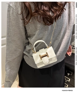 White mini square shoulder bag with gold hardware worn over grey knitwear for commute