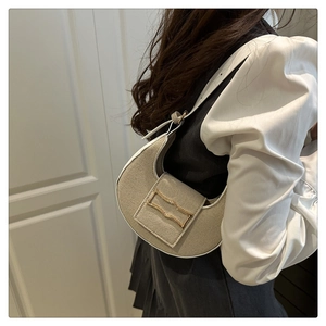 Detail of hobo bag with contrast white trim and elegant gold buckle on a model shoulder