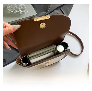 Detailansicht der braun-weißen Satteltasche Innenkapazität mit goldenem Hardware-Schloss
