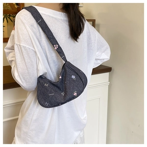 Detail of floral embroidery and white bows on dark grey denim shoulder bag for women