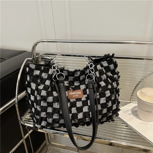 Chic black and white checkered denim tote bag with leather handles and chain detail