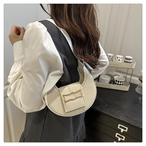 Detail of beige woven crescent bag with gold wavy buckle and white leather trim