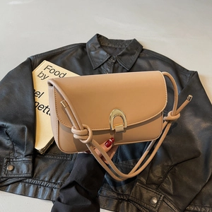 Minimalist khaki underarm bag with gold horseshoe buckle on black leather jacket