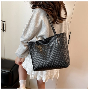 Detail view of the woven black leather tote bag with a branded fashion logo tag
