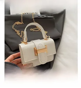 Detail of white mini crossbody bag featuring a large gold lock and elegant metal chain