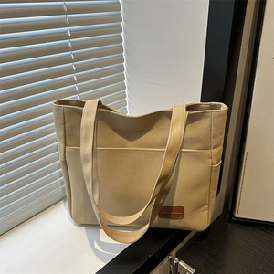 Minimalist khaki canvas tote bag with front pocket and side compartments for daily commute