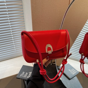 Chic red leather shoulder bag with horseshoe gold buckle and unique knotted strap detail
