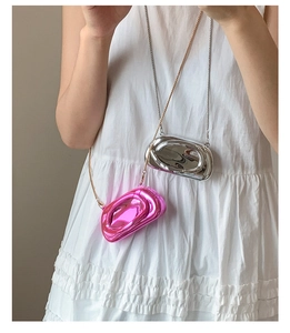 Close-up of mini liquid metal crossbody bags in bright pink and silver with chain straps