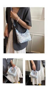 Detail of light blue geometric embroidery on handbag with pearl pendant and leather strap