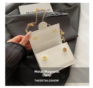 Detail shot of the golden magnetic hardware buckles on a white PU leather crossbody bag