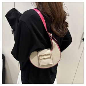 Detail of canvas crescent bag with rose pink leather trim and gold decorative buckle
