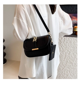 Detail of black leather crossbody bag with golden geometric buckle and matching coin purse
