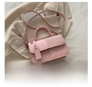 Detail of pink crossbody bag with lychee grain texture and woven fabric straw panels