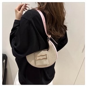 Side view of beige woven crescent bag with pink leather trim worn by a model