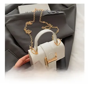 Macro shot of white leather mini bag featuring a stylish golden metal clasp and handle