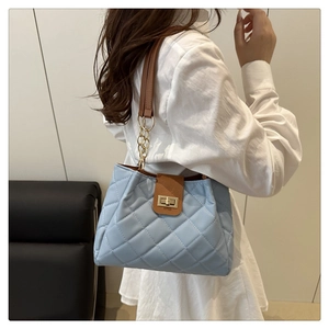 Detail of light blue quilted shoulder bag featuring gold chain strap and twist lock