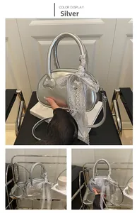 Detail of silver metallic handbag featuring white lace ribbon and heart-shaped relief detail