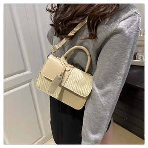 Close-up of beige crossbody bag featuring woven texture flap and brand tag detail