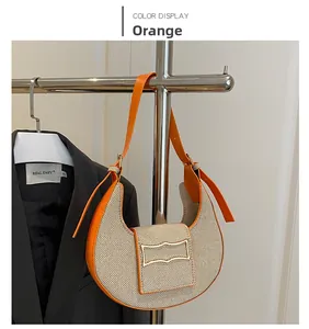 Detail of an orange crescent-shaped canvas and leather crossbody bag with metal buckle