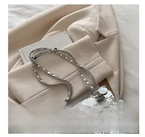 Macro detail of silver sequin bucket bag featuring metallic chain strap and chic design
