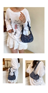 Detail of embroidered denim underarm bag with floral patterns and drawstring strap