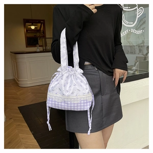 Detailed close-up of floral and plaid drawstring bucket bag with lace trim stitching