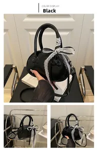 Detail of black glossy handbag featuring white lace bow and embossed bow textures