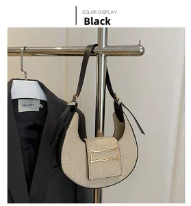Detail of woven crescent shoulder bag with black leather trim and gold buckle
