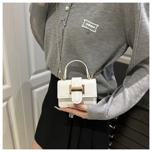 Detail of white mini crossbody bag with gold buckle and delicate chain strap on model