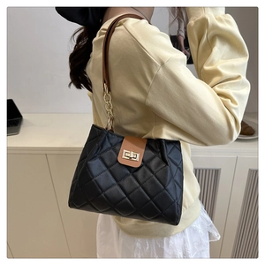 Close-up of quilted pattern and gold metal twist lock on the black leather shoulder bag