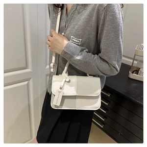 Detail view of cream white crossbody bag featuring mixed textures and woven diagonal panel