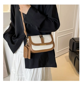 Detail of contrast stitch saddle bag with white body, brown trim and gold geometric clasp