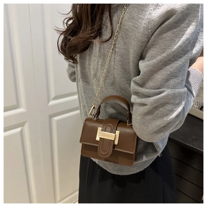 Detailed view of mini brown crossbody bag with gold chain strap on a model outfit
