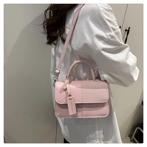 Detail view of pink patchwork crossbody bag featuring quilted texture and fashion tag